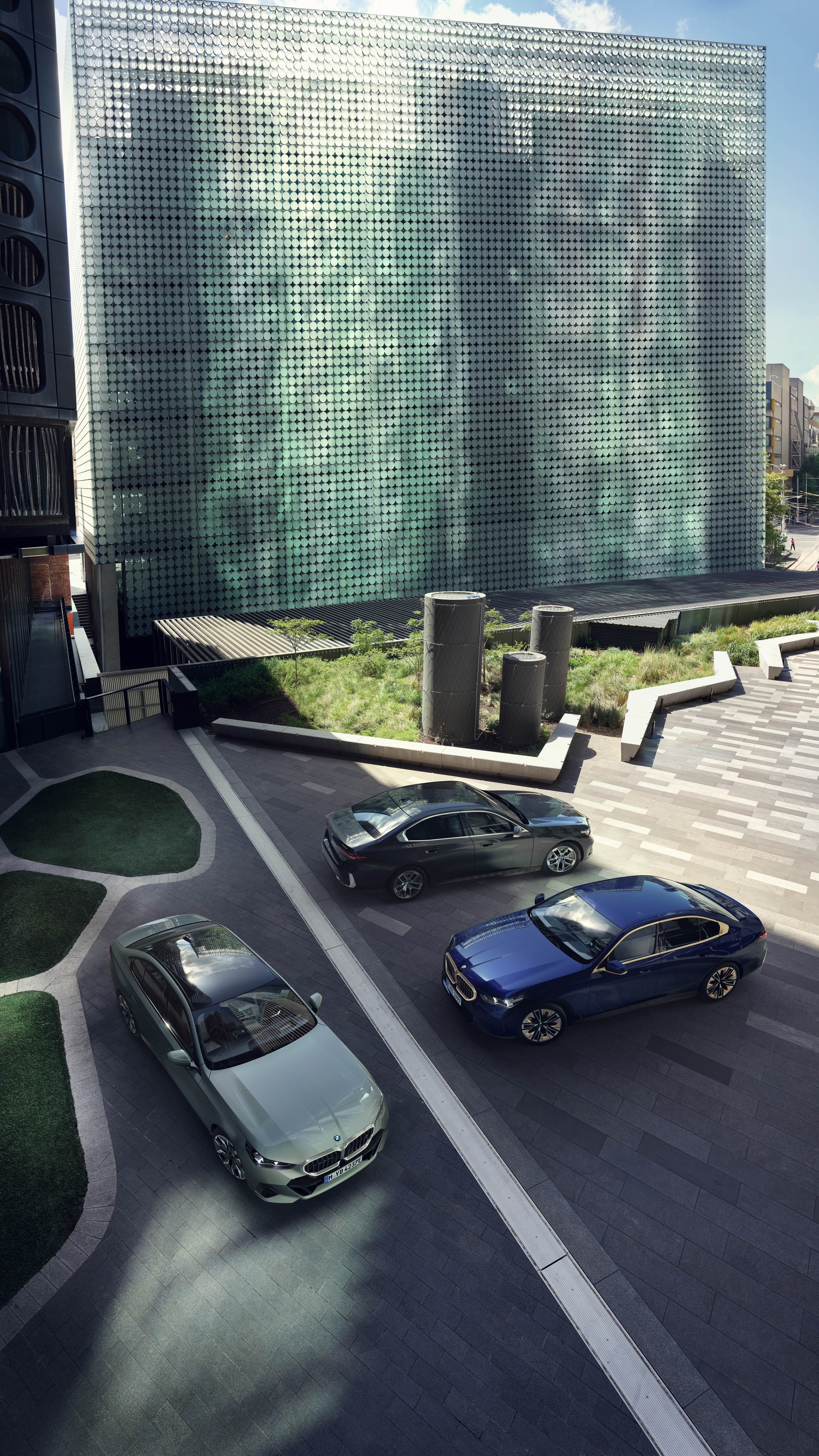 3 BMW Fahrzeuge in einem futuristischen Setting geparkt