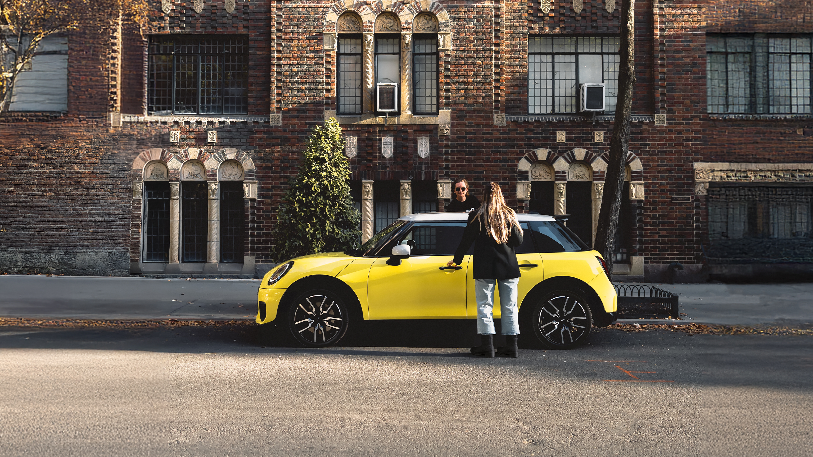 Ein junges Pärchen steigt in einen gelben MINI Cooper C ein.