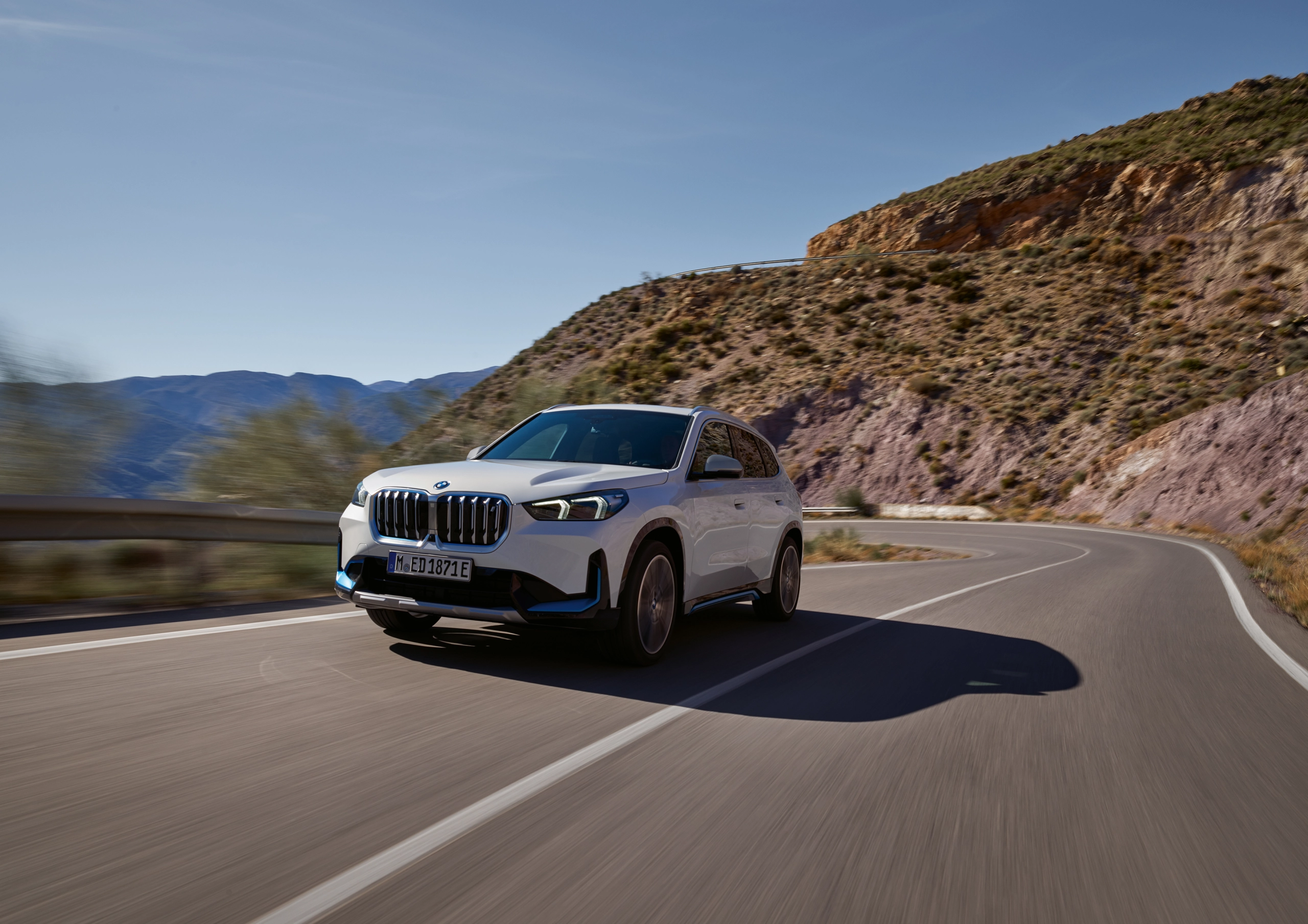 Ein BMW iX1 auf einer Serpentine in den Bergen